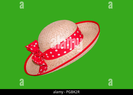 stylish woman, straw hat with sun with red ribbon with white mugs and with a beautiful bow, on a green background Stock Photo