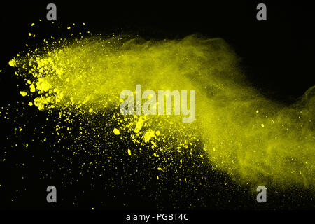 Abstract of yellow powder explosion on black background. Yellow powder splatted isolate. Colored cloud. Colored dust explode. Paint Holi. Stock Photo