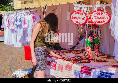 CLUJ-NAPOCA, ROMANIA - JULY 29, 2018: woman choosing embroidered towels at ethnic souvenir store Stock Photo