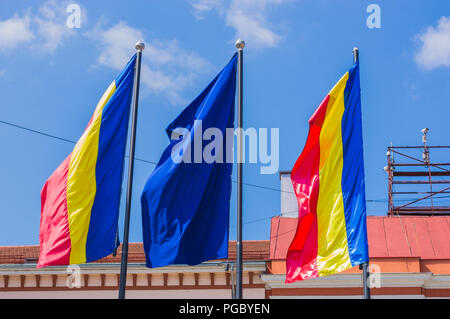 Romanian and EU flags waving on background of historic building facade Stock Photo