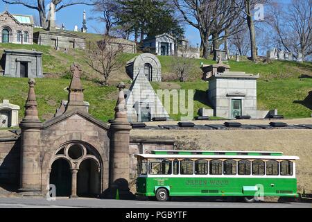 Brooklyn, NY: A trolley waits for passengers below obelisks and mausoleums on a hillside in historic Green-Wood Cemetery, founded in 1838. Stock Photo