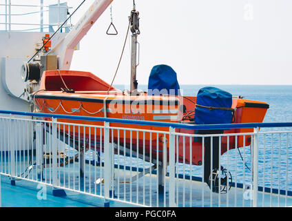 Orange lifeboat on deck of a sea vessel in the ocean Stock Photo