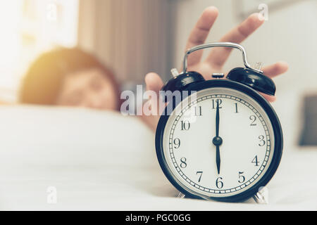 lazy to wake up girl hand off alarm clock ring on bed at morning monday Stock Photo