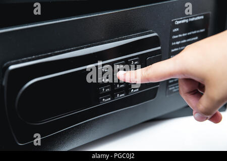 Digital safety safe box in hotel room service with hand using finger at password key pad Stock Photo