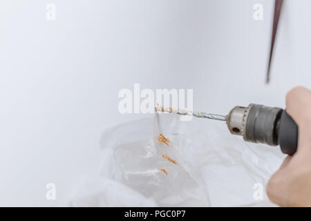 home renovation closeup hand using drill to drilling bit hole on the wall to install floating shelves Stock Photo