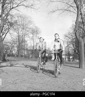 1940s couple on bicycles. A young couple is riding their bicycles on a sunny spring day. They have practical bags attached to the racks of the bicycles where they could transport the picnic food.  Sweden 1947. Photo Kristoffersson AB11-11 Stock Photo