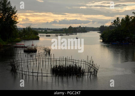 An atmospheric landscape photographed at dusk on a tributary river between the towns of Hoi An and An Bang, in Central Vietnam. In it, the silhouette  Stock Photo