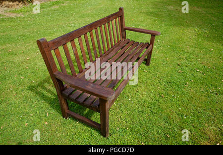 wodd garden bench on a green mowed lawn. Stock Photo