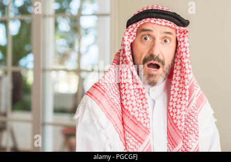 Middle age arabian man at home scared in shock with a surprise face, afraid and excited with fear expression Stock Photo