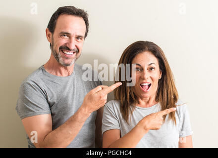 Middle age couple, woman and man very happy pointing with hand and finger Stock Photo
