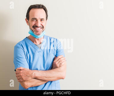 Senior doctor man using mask with a happy face standing and smiling with a confident smile showing teeth Stock Photo