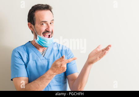 Senior doctor man using mask very happy pointing with hand and finger Stock Photo