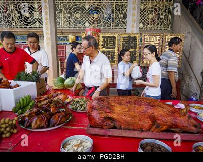 George Town, Penang, Malaysia. 25th Aug, 2018. People in Leong San Tong Khoo Kongsi Temple walk around the banquet for the spirits on Ghost Day, the full moon day (or night) that falls in the middle of Hungry Ghost month. The Ghost Festival, also known as the Hungry Ghost Festival is a traditional Taoist and Buddhist festival held in Chinese communities throughout Asia. Ghost Day, is on the 15th night of the seventh month (25 August in 2018). During Ghost Festival, the deceased are believed to visit the living. In many Chinese communities, there are Chinese operas and puppet shows and elabo Stock Photo