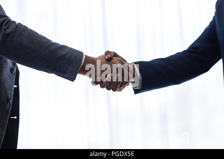 Close up of two business men shaking hands with each other after a deal, with focus on hand shake. Stock Photo
