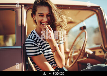 Portrait of beautiful young woman laughing in the car. Woman taking a break on road trip. Stock Photo