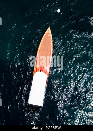 Aerial view of a beautiful orange racing boat sailing on a transparent ...