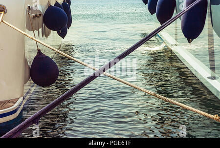 Twisted Marine Anchoring Ropes over the blue water between two yachts. Stock Image. Stock Photo