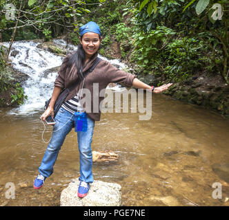 Asian woman balancing on a rock in the middle of a stream north of Chiang Mai in the mountains. With photo release: yes Stock Photo