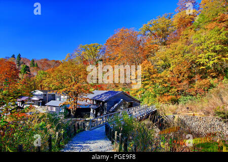 Rustic ryokan Magoroku Onsen among colorful autumn forest with blue sky in hot spring resorts of Nyuto Onsenkyo, Akita Prefecture, Japan Stock Photo