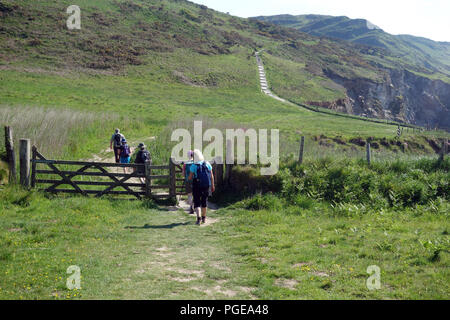 A Group of Walkers Going Through a Wooden Gate at Rockham Bay Heading for Morte Point on the South West Coastal Path, Devon, England, UK. Stock Photo