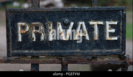 A private sign on a metal railing rusting through the cracked black and white paint Stock Photo