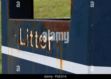A close up of the litter sign on the side of a rusted blue bin with a white stripe under the letters Stock Photo