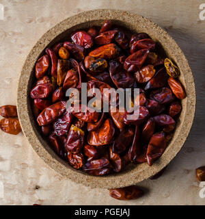 Pequin chilies in a small cork bowl against a birdseye maple background, shot flat-lay (Capsicum annuum var. glabriusculum) Stock Photo