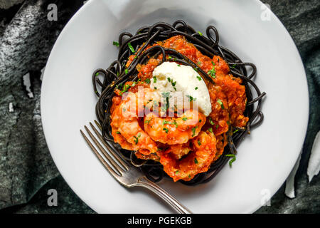 Spot prawns in a saffron tomato sauce with mascarpone cheese, served over nero di seppia (cuttlefish ink) spaghetti Stock Photo