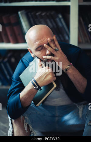Depressed man with book sitting on floor head in hands. Tragedy concept Stock Photo