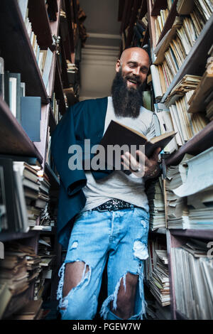Happy smiling man reading book in bookshelves background. education Stock Photo