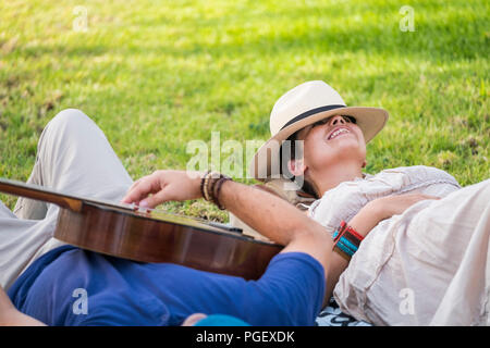 happy and relaxed cheerful couple laying down on the natural grass and enjoy the outdoor leisure activity with a good weather in spring season. man pl Stock Photo