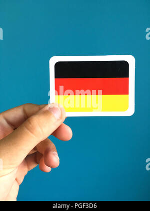 Human hand holding small card with national flag of Germany Stock Photo