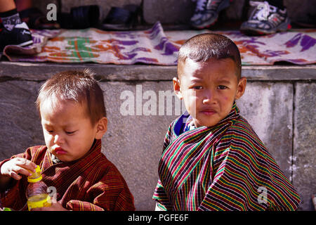 Two young boys in traditional costume known as a Gho. Photographed at the colourful Thimpu Tshechu Festival, one of Bhutan's grandest  celebrations Stock Photo