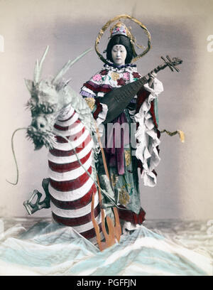 [ c. 1890s Japan - Japanese Goddess of Love ] —   A woman portrays Benten (also known as Benzaiten), the Japanese goddess of love, eloquence, wisdom, the arts, music, knowledge, good fortune and water. She is the patroness of geishas, dancers, and musicians.  Albumen photograph sourced by Kozaburo Tamamura (1856-1923?), 1890s, for 'Japan, Described and Illustrated by the Japanese', Shogun Edition edited by Captain F Brinkley. Published in 1897 by J B Millet Company, Boston Massachusetts, USA.  19th century vintage albumen photograph. Stock Photo