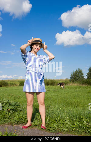 Girl shows her fingers like a cow's horns in field Stock Photo