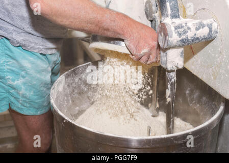 Loading flour into an industrial bakery dough mixer. Stock Photo