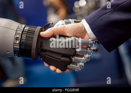 Hand of a businessman shaking hands with a Android robot. The concept of human interaction with artificial intelligence. Stock Photo