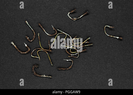 Bunch of very old and rusty fishing hooks on black background surface Stock Photo