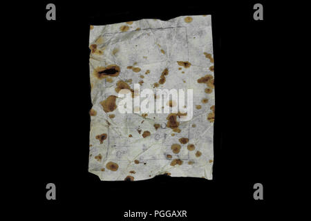 Very old and aged white paper sheet with brown spots on it isolated on black background surface Stock Photo