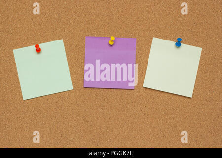 Three colorful sticky notes with pushpins and blank space, isolated on cork background, school concept Stock Photo