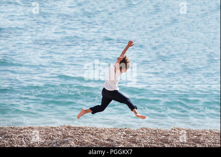 healthy little kid running along sea shore on summer holiday beach on