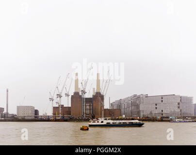 View across river with hazy sky and Thames clipper. Battersea Power Station, under construction, London, United Kingdom. Architect: Sir Giles Gilbert  Stock Photo