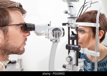 Slit Lamp eye control with the Ophthalmologist /pretty woman during an exam with Slit Lamp / the ophthalmologist in eyes clinic doing cornea and retin Stock Photo