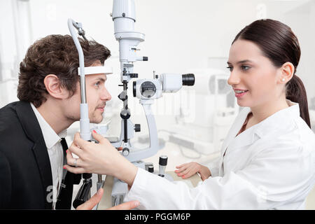 Eye Woman Doctor Adjusting Slit Lamp / handsome man during a cornea exam / the oculist in eyes clinic doing crystalline lens diagnostic / high technol Stock Photo