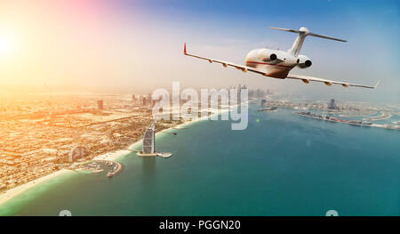 Private jet plane flying above Dubai city in beautiful sunset light. Modern and fastest mode of transportation, business life. Stock Photo