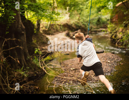 Boy swinging on rope swing Stock Photo