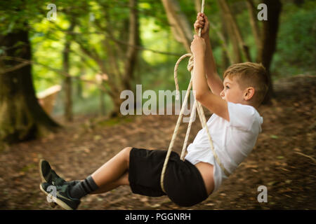 Boy swinging on rope swing Stock Photo