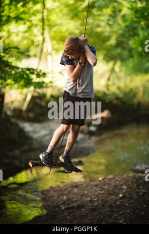 Boy swinging on rope swing Stock Photo