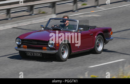 A classic Triumph TR6 drives along the road Stock Photo