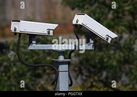 Two large white security cameras mounted on a pole. Stock Photo